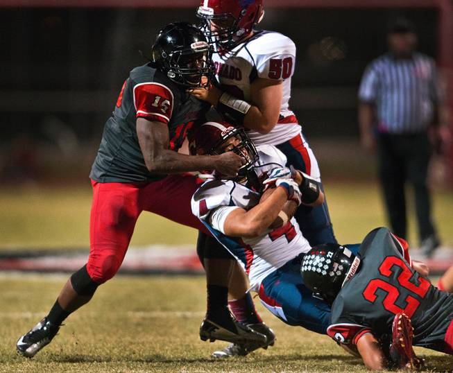 Las Vegas High School's Thomas Dorsey, 15, takes down Coronado's Justin Balanga, 4, runner by his face mask with help from teammate Jacob Bowden, 22, during their football game on Friday, December 02, 2015.