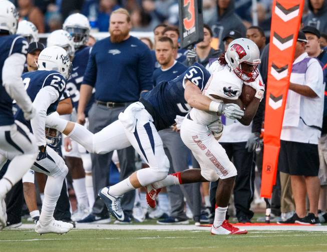 After a reception, UNLV's Devonte Boyd (83) works his way up field with UNR's Alex Bertrando (56) flying in for the tackle during the Mountain West game between the UNLV Rebels and the UNR Wolfpack at Mackay Stadium in Reno, Nevada.