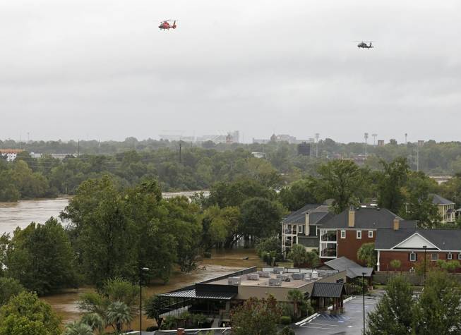 Helicopters fly over the Congaree River, swollen with floodwaters, near the Gervais Street bridge in West Columbia, S.C., on Sunday, Oct. 4, 2015. Hundreds were rescued from fast-moving floodwaters Sunday in South Carolina as days of driving rain hit a dangerous crescendo that buckled buildings and roads, closed a major East Coast interstate route and threatened the drinking water supply for the capital city.
