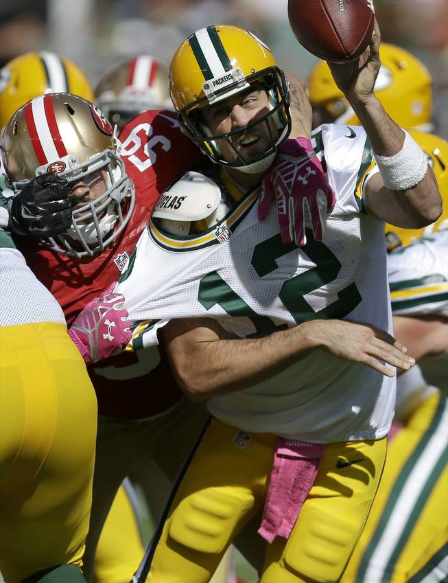 Green Bay Packers quarterback Aaron Rodgers, right, gets rid of the ball as he is pressured by San Francisco 49ers linebacker Aaron Lynch during the first half of an NFL football game Sunday, Oct. 4, 2015, in Santa Clara, Calif.