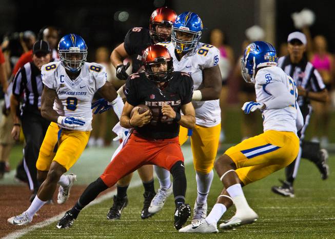UNLV QB Kurt Palandech, 14, looks to evade a tackle by the San Jose State defense during a run at Sam Boyd Stadium on Saturday, October 10, 2015.