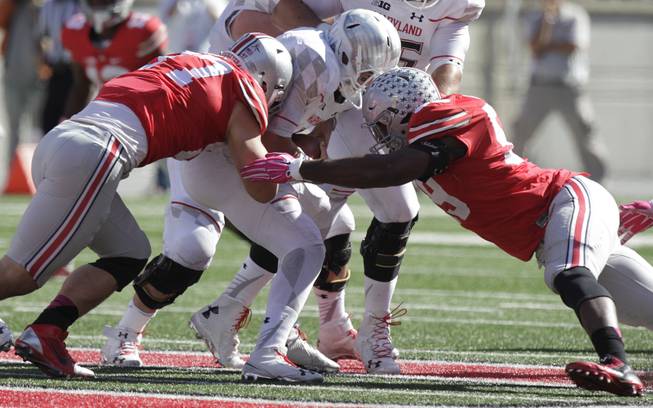 Ohio State defensive lineman Joey Bosa, left, and defensive lineman Tyquan Lewis, right, sack Maryland quarterback Perry Hills during the fourth quarter of an NCAA college football game Saturday, Oct. 10, 2015, in Columbus, Ohio. Ohio State beat Maryland 49-28.