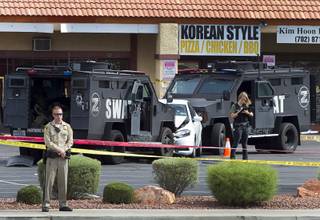 A Metro Police officer stands by as a crime scene analyst takes notes after an officer-involved shooting in a strip mall on Jones Boulevard near Spring Mountain Road Thursday, Oct. 15, 2015.
