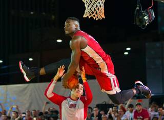 UNLV's Ike Nwamu, 0, gets fancy with an assist from teammate Austin Starr, 20, while soaring to the hoop during a dunk contest apart of the Runnin Rebel Madness basketball season tipoff celebration party downtown at the Las Vegas Events Center on Thursday, October 22,  2015.  .