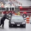 A Dalls Fire Rescue responder makes his way over to a stalled vehicle to check on the driver still inside on Friday, Oct. 23, 2015, in Dallas. The vehicle stalled after the road quickly flooded during a heavy rain fall. 