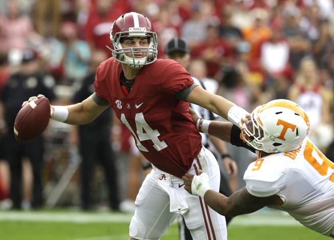 Alabama quarterback Jake Coker stiff arms Tennessee defensive end Derek Barnett as he tries to get away from pressure Saturday, Oct. 24, 2015, in Tuscaloosa, Ala.