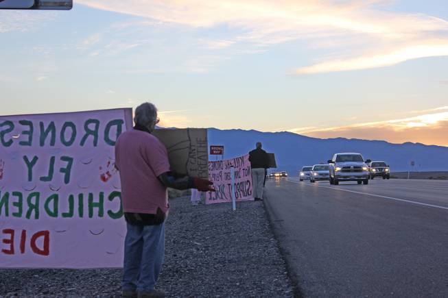 Anti-drone activists with the group Code Pink hold signs for cars turning into Creech Air Force Base Monday morning, Oct. 26, 2015.