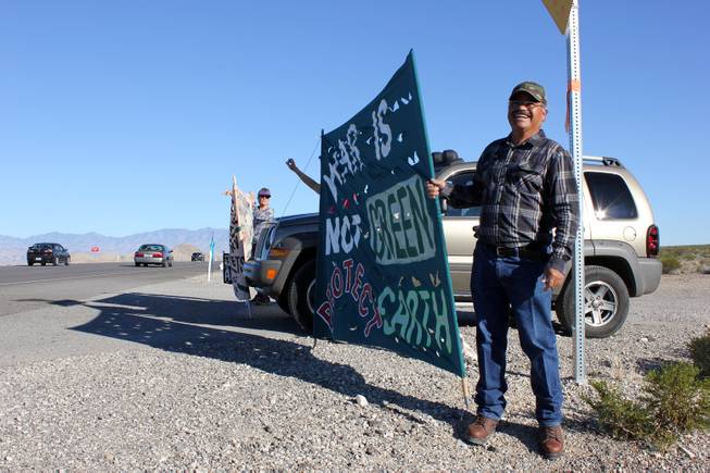 Indian Springs resident Ruben Beltran holds a poster Monday, Oct. 26, 2015, during a protest session to highlight the environmental effects of war. Beltran was across the highway from Creech Air Force Base as part of a weeklong anti-drone protest.
