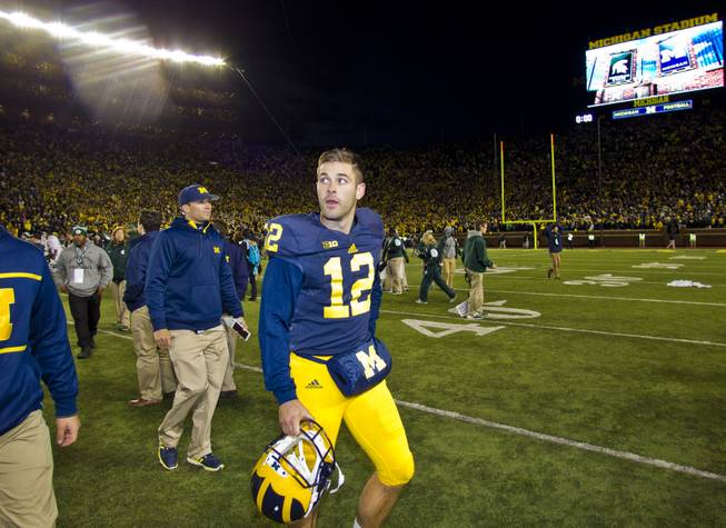 Michigan punter Blake O'Neill (12) walks off the field after an NCAA college football game against Michigan State in Ann Arbor, Mich., Saturday, Oct. 17, 2015. Michigan State's Jalen Watts-Jackson grabbed a flubbed punt by O'Neill and lumbered 38 yards into the end zone for a touchdown on the final play of the game, giving No. 7 Michigan State a shocking 27-23 win over No. 12 Michigan.