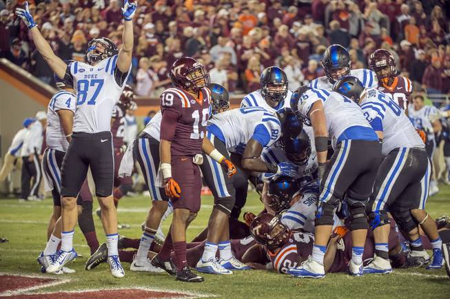 Duke wide receiver Max McCaffrey (87) celebrates after Duke quarterback Thomas Sirk, bottom, crosses the goal and scores an extra point to win after four overtime periods against Virginia Tech during an NCAA college football game, Saturday, Oct. 24, 2015, at Lane Stadium in Blacksburg, Va. Duke defeated Virginia Tech 45-43. 