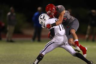 Centennial's Savon Scarver (11) is taken down by Arbor View's Alex Sims (21) during a game against the Centennial at Arbor View Thursday, Oct. 29, 2015.