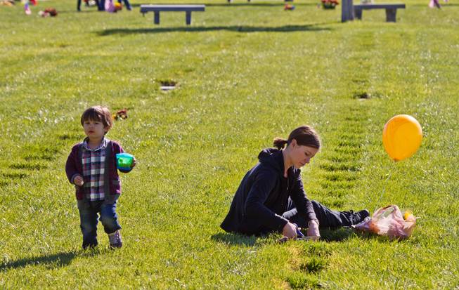 Courtney Nelson (right) with son Fox, 2, trims up the grass about her father Emil Ken Kluever's gravestone on Veteran's Day within the Southern Nevada Veterans Memorial Cemetery in Boulder City on Wednesday, November 11, 2015.  He was a colonel and served in Vietnam, his father buried nearby  was a colonel as well.