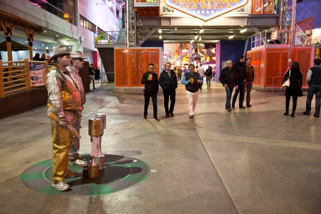 From left, Dennis Patterson and Chad Fritz, living silver statues, stand lifelessly still in a pre-designated spot on the Fremont Street Experience, Tuesday Nov. 17, 2015. A new regulation takes effect today that brings order to the chaos of street performers.