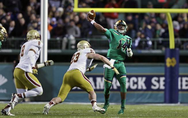 Notre Dame quarterback DeShone Kizer (14) throws a pass as he is pressured by Boston College defensive end Kevin Kavalec (93) and defensive lineman Harold Landry (8) at Fenway Park.