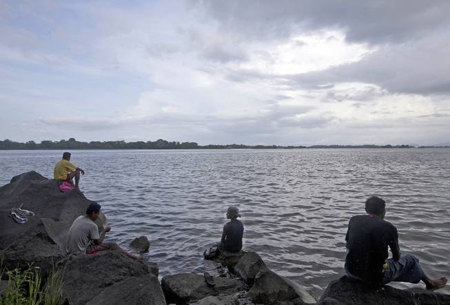 A group of men sits on rocks, while fishing on the shores on the shores of Cocibolca Lake, also known as Lake Nicaragua, in the colonial city of Granada, Nicaragua, Thursday, July 16, 2015. Nicaragua plans to create a canal that's expected to rival that of Panama, which would run through this lake.