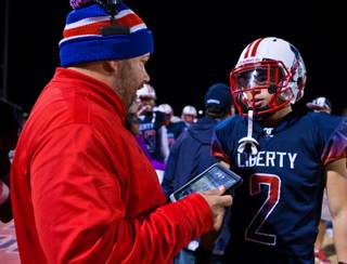 Liberty High School head coach Richard Muraco utilizes hand-held technology on the sidelines while consulting with Ethan Dedeaux (2) to give an edge to his football players and coaches while facing Green Valley in their high school state quarterfinal game at Liberty on Friday, November 20, 2015.