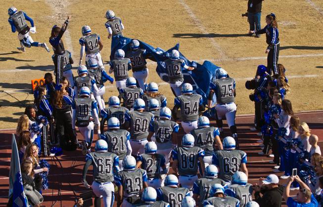 Basic players stream onto the field through a paper banner to face Liberty high school in their state semifinals football game at Basic Academy of International Studies on Saturday, November 28, 2015.