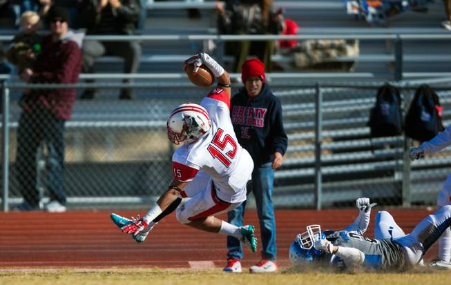 Liberty's Stephon Stowers (15) leaps for a few extra yards after a shoestring tackle by Basic's Kyle Grismanauskas (2) during their high school state semifinals football game at Basic Academy of International Studies on Saturday, November 28, 2015.