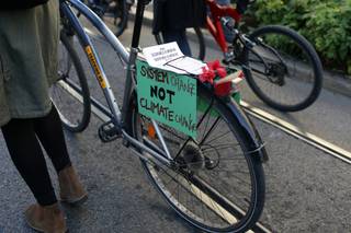 A woman pushes a bicycle decorated with protest signs while taking part in a World Climate March in Lisbon, Sunday, Nov. 29 2015. Rallies were organized around the world on Sunday, calling on all government leaders to halt climate change on the eve of a major conference in Paris. (AP Photo/Armando Franca)