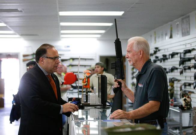 Sales associate Mike Conway, right, shows Paul Angulo a semiautomatic rifle Dec. 9, 2015, at Bullseye Sport gun shop in Riverside, Calif. The massacre at Sandy Hook Elementary School in which a mentally disturbed man killed 26 children and teachers galvanized calls across the nation for tighter gun controls. But in the three years since, many states have moved in the opposite direction, embracing the National Rifle Association’s response that more “good guys with guns” are what’s needed to limit the carnage of mass shootings.