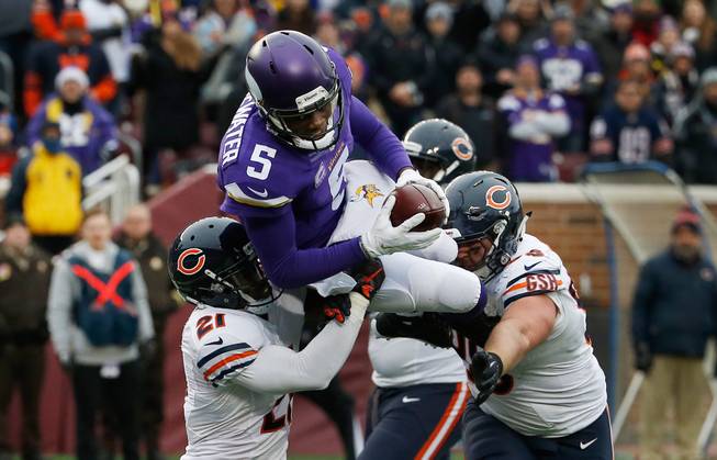 Minnesota Vikings quarterback Teddy Bridgewater, top, lifted by Chicago Bears strong safety Ryan Mundy, left, prepares to fall into the end zone for a rushing touchdown Sunday, Dec. 20, 2015, during the second half of an NFL football game in Minneapolis.