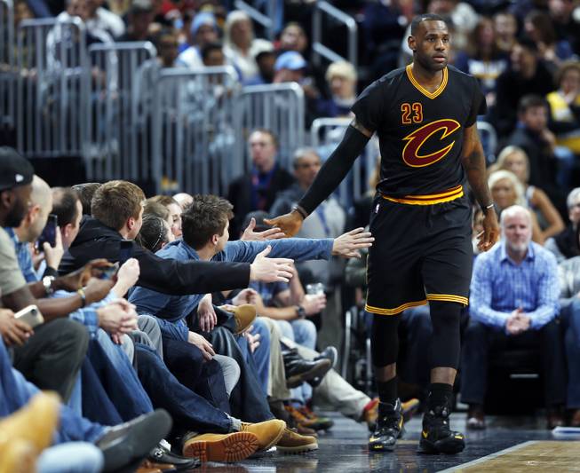 Fans in court side seats reach out their hands to congratulate Cleveland Cavaliers forward LeBron James after he drew a foul against the Denver Nuggets in the second half of an NBA basketball game Tuesday, Dec. 29, 2015, in Denver. Cleveland won 93-87. 