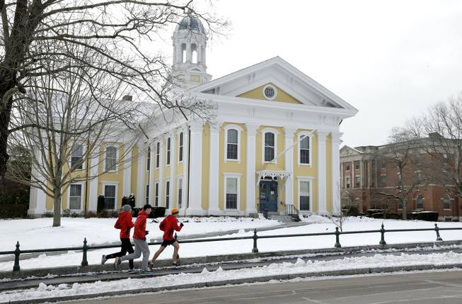In this Thursday, Jan. 14, 2016 photo, runners make their way along a sidewalk on the campus of Wheaton College, in Norton, Mass. More than 1,000 miles away there's another Wheaton College, in Wheaton, Ill. Though people often confuse the schools, the two aren't related. 