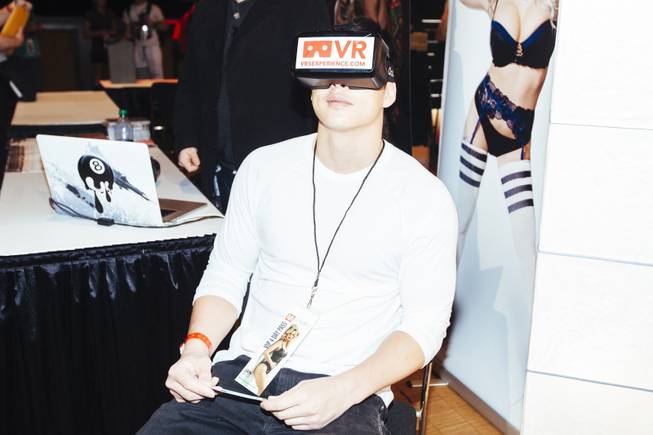 An attendee demonstrates a virtual-reality headset from VRSexperience during the ...
