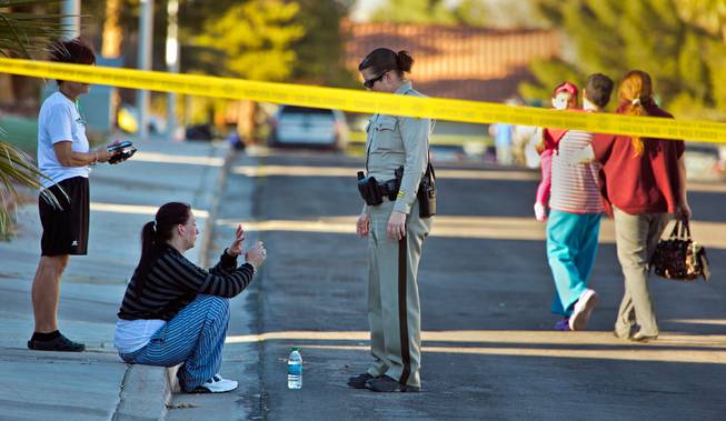 After being interviewed by Metro Police a woman sits and looks at a possible injured hand near an officer, a homicide call along S. Kennewick Drive still in progress on Tuesday, February 9, 2016.