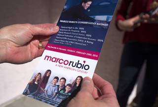 A resident reads a information on Republican Presidential Candidate Sen. Marco Rubio (Fla.) as Rubio volunteers canvass a neighborhood in Summerlin Sunday, Feb. 21, 2016.