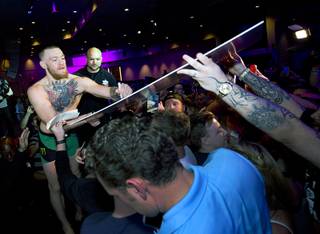 Conor McGregor signs a poster for a fan during open workouts for UFC 196 at MGM Grand Wednesday, March 2, 2016. UFC 196 takes place Saturday at the MGM Grand Garden Arena.