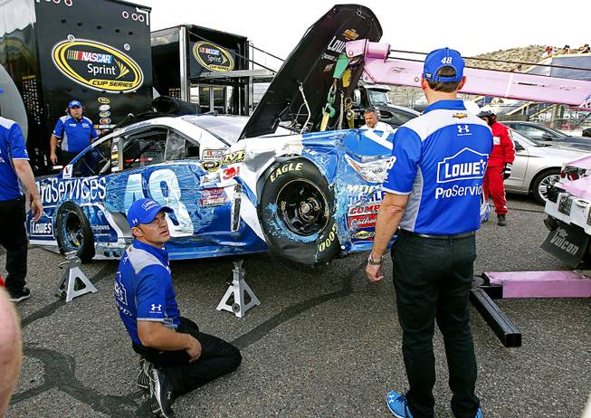 The pit crew of Jimmie Johnson look over the damage to Johnson's car after he crashed in Turn 2 during NASCAR Sprint Cup Series qualifying at Phoenix International Raceway, Friday, March 11, 2016, in Avondale, Ariz.