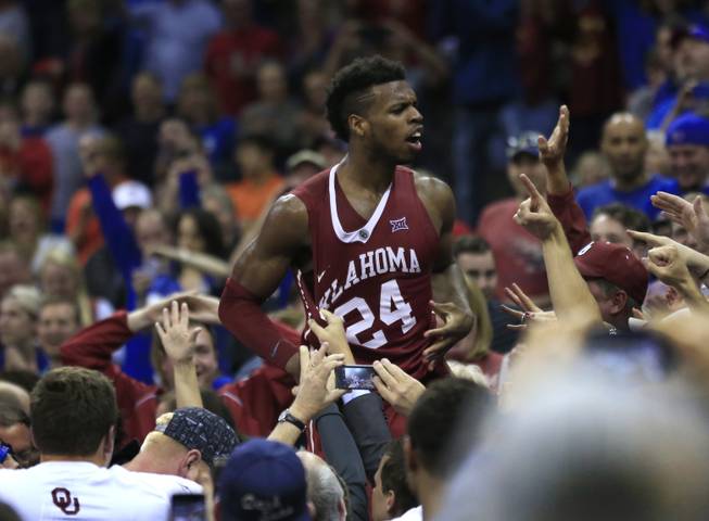 Oklahoma guard Buddy Hield (24) celebrates with fans after thinking he had scored the winning basket during NCAA college basketball game against West Virginia in the semifinals of the Big 12 conference men's tournament in Kansas City, Mo., Friday, March 11, 2016. Replays showed the shot was after time expired. West Virginia defeated Oklahoma 69-67. 