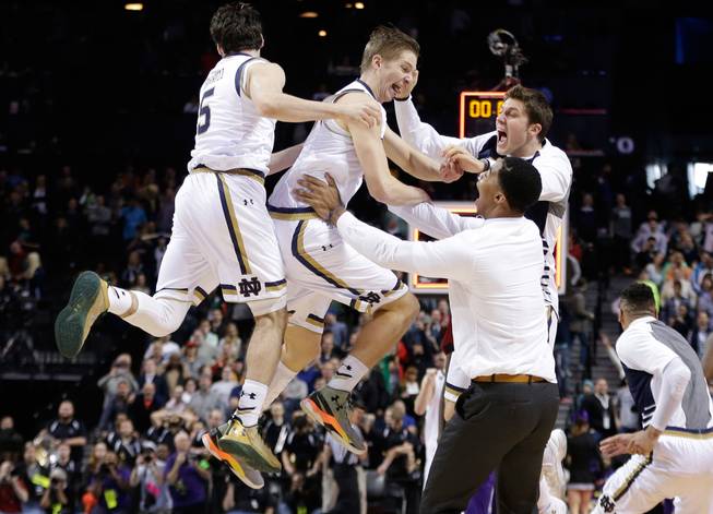 Notre Dame's Rex Pflueger, center, and Matt Farrell, left, celebrate with teammates Sunday, March 20, 2016, after a second-round men's college basketball game in the NCAA Tournament in New York. Notre Dame won 76-75.