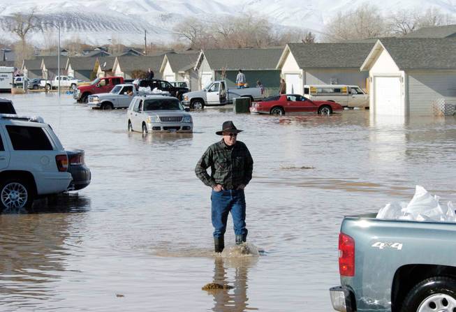A man walks Jan. 5, 2008, amid the flooded area in Fernley, Nev. Eight years, dozens of lawyers and hundreds of thousands of documents later, more than 200 Nevada flood victims are finally going to get paid for damages suffered when a century-old irrigation canal burst and sent a wall of water into their homes in 2008.