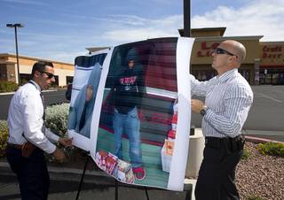 Metro Police officers attach suspect photographs to a board before a Metro Police news conference outside Lee's Discount Liquors, 8785 W Warm Springs Rd., Tuesday, April 19, 2016. Police are asking for the public's assistance in capturing three men who killed an employee of the store during a robbery Monday night.