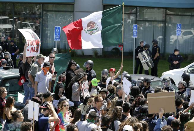 A protester against Republican presidential candidate Donald Trump waves a flag of Mexico outside of the Hyatt Regency hotel where the California Republican Party 2016 Convention is taking place in Burlingame, Calif., Friday, April 29, 2016. 