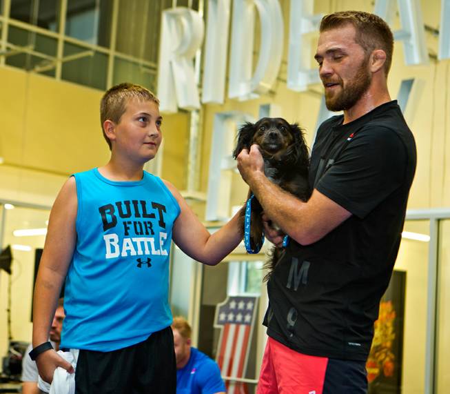 Maddux Maple, 10, spends time on the mat with Bantamweight Bryan Caraway and his dog during UFC Fight Night workouts at the Las Vegas Harley Davidson store on Thursday, May 27, 2016.  Maple is a cancer survivor and fan of the sport.