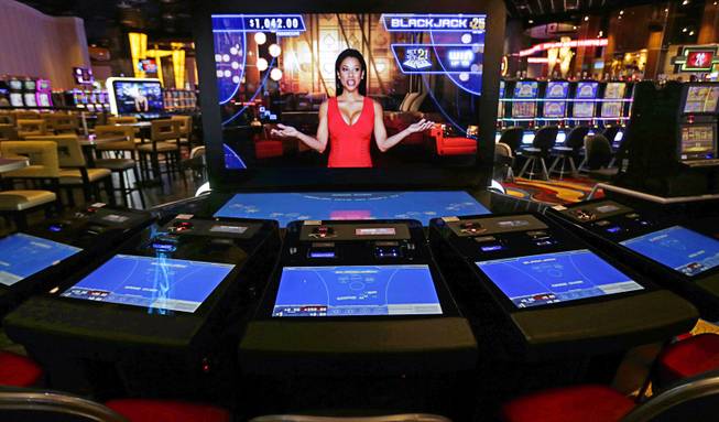 In this June 23, 2015 file photo, an automated dealer asks for players to take a seat at a black jack video slot machine on the floor of the Plainridge Park Casino, in Plainville, Mass. Massachusetts is set to launch this week a first-in-the-nation system allowing slot players to limit their bets.