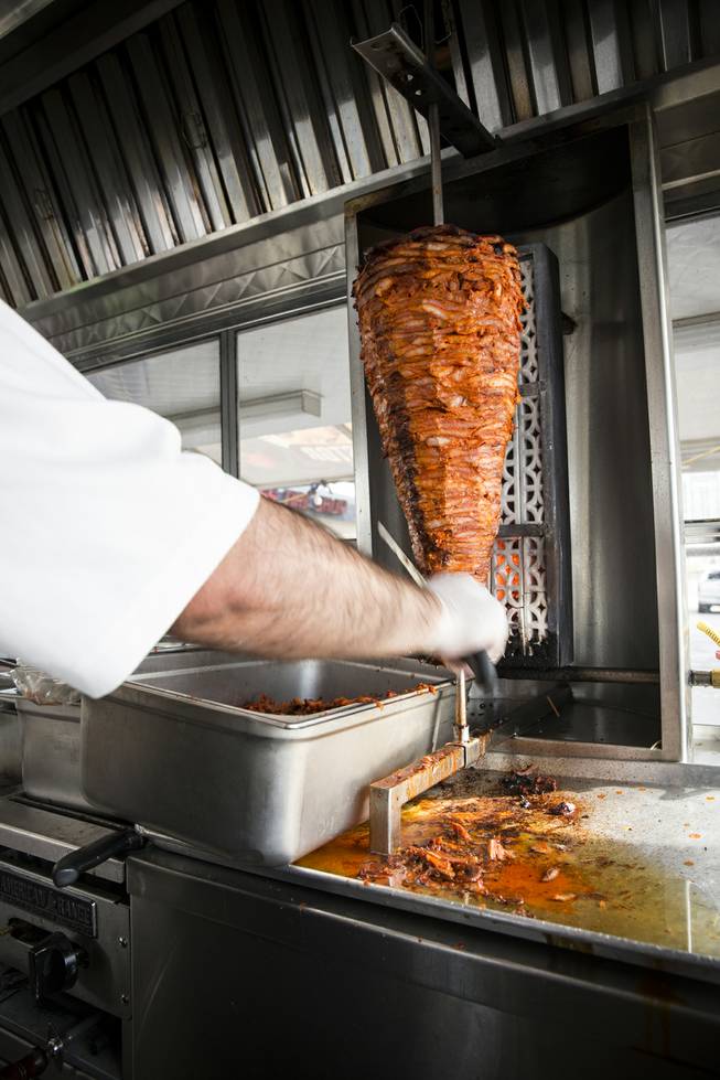 Chef Francisco Cruz at the Taqueria El Buen Pastor taco truck slices meat off the rotisserie for an order, Monday, June 6, 2016.