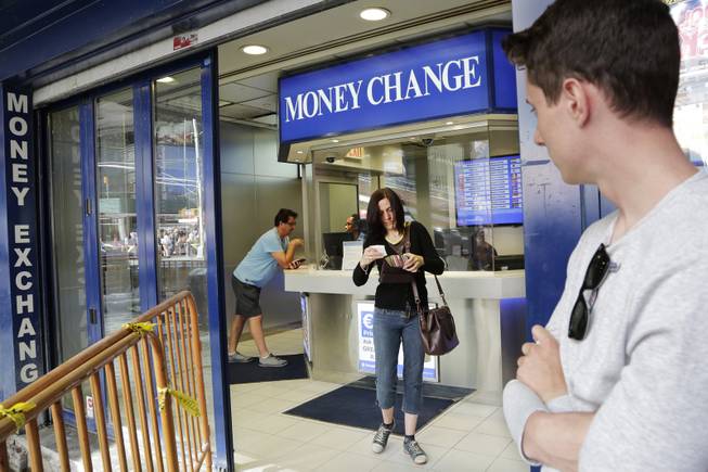 Claire Hunt, center, of Reading, England, changes pounds for dollars, Friday, June 24, 2016, at a money exchange in New York. Britain voted to leave the European Union after a bitterly divisive referendum campaign, toppling the government Friday, sending global markets plunging and shattering the stability of a project in continental unity designed half a century ago to prevent World War III. "I think the exchange went down about eight percent (from yesterday)," said Hunt, who is vacationing with her son, Jacob Wood, right. "It's scary. I don't know what we are going home to." 