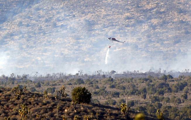 A helicopter drops water on a brush fire near Lovell Canyon Road and State Route 160 Sunday, June 26, 2016.