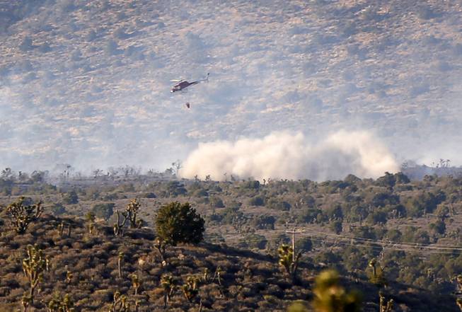 Smoke rises after a helicopter water drop at a brush fire near Lovell Canyon Road and State Route 160 Sunday, June 26, 2016.