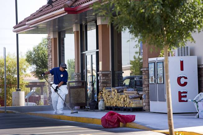 A worker with H2O Environmental cleans up in front of the Maverik gas station at Bermuda Road and Cactus Avenue after a fatal shooting Sunday, June 26, 2016. 