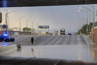 A Nevada Highway Patrol trooper stands by storm run-off at the railroad underpass on Sunset Road between Decatur Boulevard and Arville Street after a thunderstorm dropped heavy rain and hail in the area Thursday, June 30, 2016. The roadway was closed in both directions until the run-off receded. 