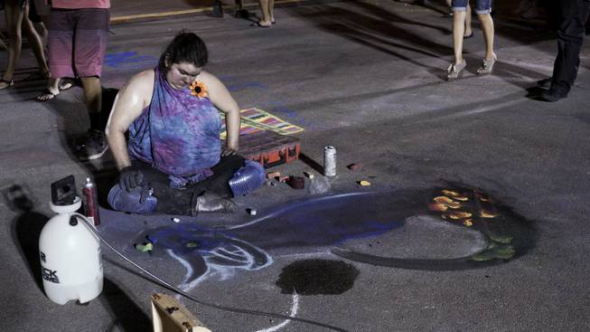 An artist looks over her chalk drawing during First Friday festivities at the Arts District in downtown Las Vegas, July 1, 2016.