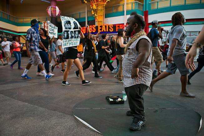 A performer watches as the Black Lives Matter organization moves along the Fremont Street Experience during another protest and march in downtown Las Vegas on Saturday, July 16, 2016.