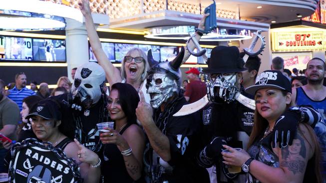 A passerby photo bombs an NFL Raiders fan photo session during a Raider Nation hosted pub crawl in Downtown Las Vegas Friday, July 22, 2016.