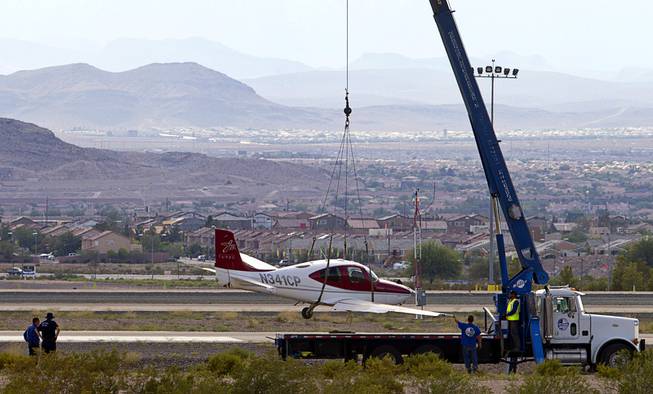 A small plane is lifted onto a flatbed after the pilot crash-landed short of the runway at the Henderson Executive Airport in Henderson Thursday, July 28, 2016. No one was injured in the accident, officials said. 