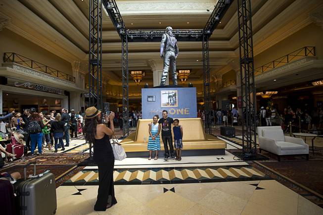 A "Michael Jackson One" cast member poses with Makhayla, Matthews, 9, of Henderson and her brother DJ Matthews, 7, following an unveiling ceremony in the Mandalay Bay lobby Thursday, July 28, 2016. The 10-foot-tall statue is on loan from the Estate of Michael Jackson.
